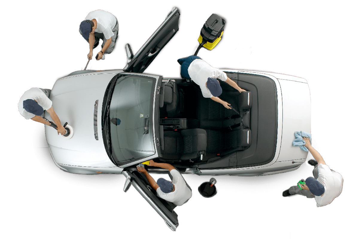 Mehrere Mitarbeiter reinigen und polieren gemeinsam ein weißes Auto von innen und außen, jeder übernimmt eine spezielle Aufgabe für eine gründliche Fahrzeugpflege.